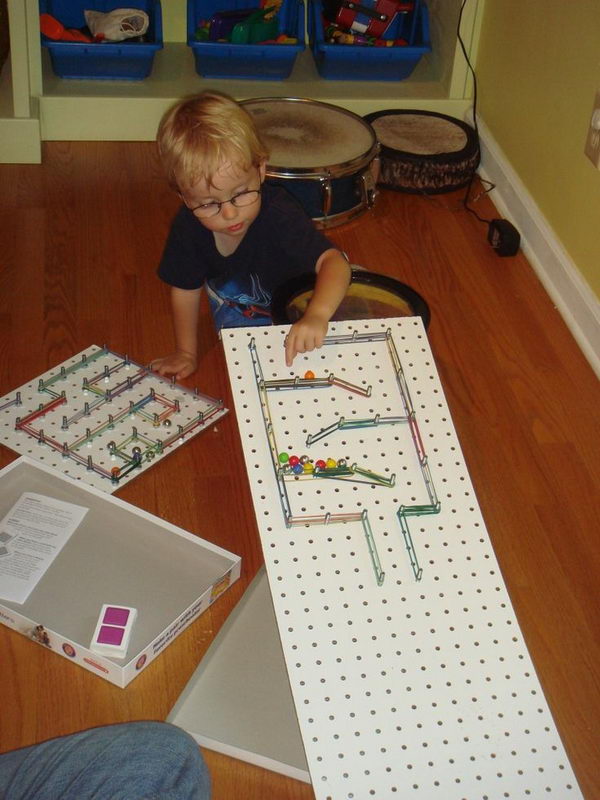 Simple Rube Goldberg Machine for Kid, DIY marble maze using pegboard on an incline, colorful rubber bands, and marbles. The goal was to hit and topple as many foam pieces (inside the box) as possible.