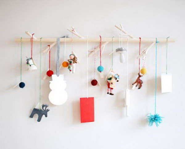 Ornaments hung from a branch as a modern advent. This advent calendar is a fun, popular way for kids and adults to count down the days until Christmas. Kids would love the surprises hidden behind each day.