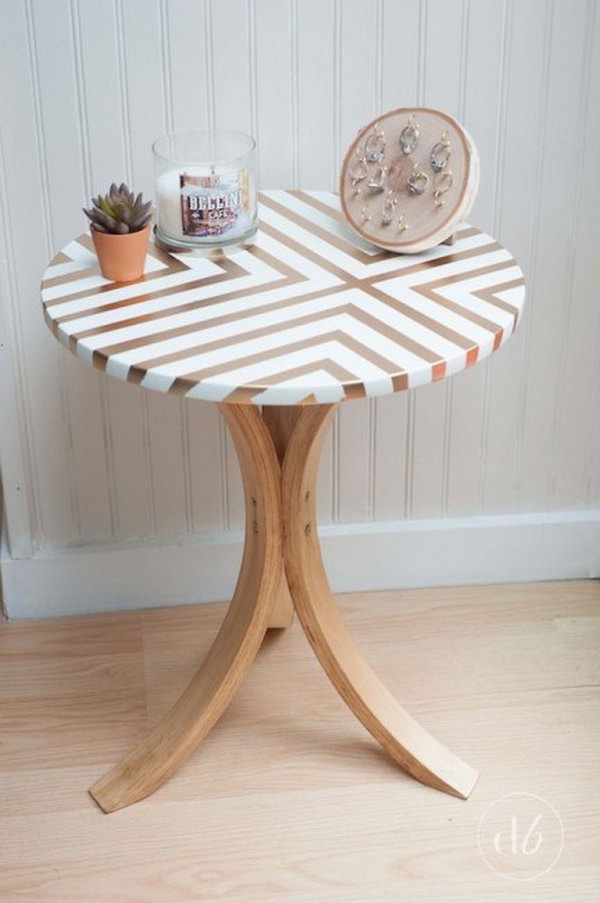 Takes an old Ikea table and gives it a gorgeous and trendy side table makeover using some tape, gold spray paint, and wood stain. 