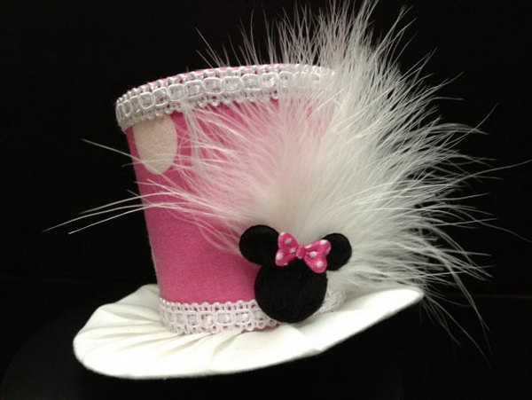 This adorable pink minnie mouse mini top hat is the perfect choice for your lovely daughter. White feathers are attached to the side along with cute Minnie Mouse head with pink polka dot bow to complete this adorable look! 