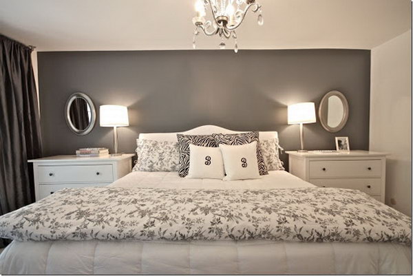 This master bedroom looks very nice, big and tall with a dark gray accent wall and the practical chests instead of small nightstands.