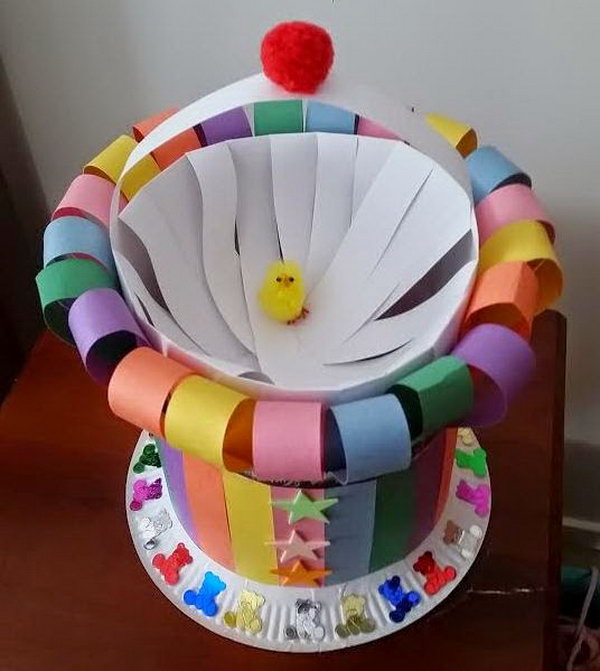 Colorful Strips Easter Bonnet. Roll the paper into a cylinder and cut the strips, glue the opposing ends and leave one to make the handle. Cut colorful strips to apply this pattern around the cylinder. Stick this with the plate and finish off this Easter hat with some foam stars or teddy confetti.