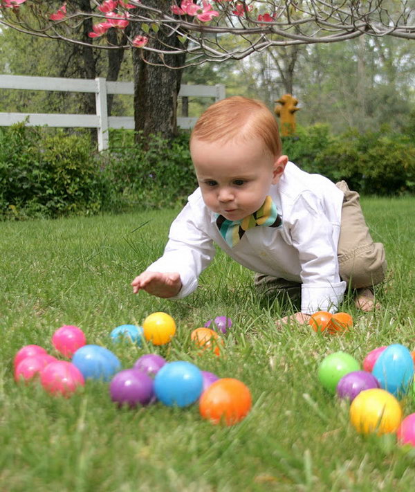 Adorable Easter Happening. Throwing some colorful plastic Easter eggs on the lawn. The kid must be eager to hold the colorful eggs. When he is crawling to catch one, take the shoot.