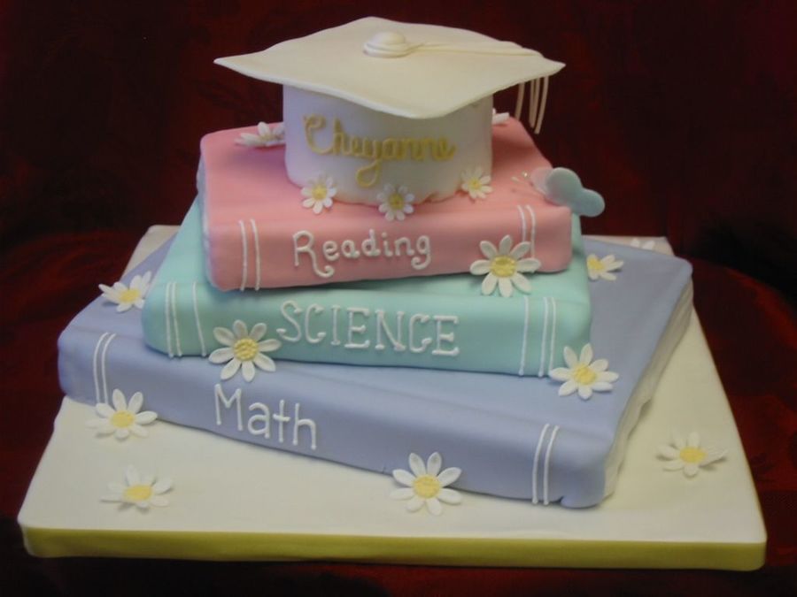 Stacked Book Graduation Cake. This adorable graduation cake features a stacked book design in soft colors. It is made up of chocolate fudge, vanilla fondant as well as beautiful gumpaste flower and butterfly.