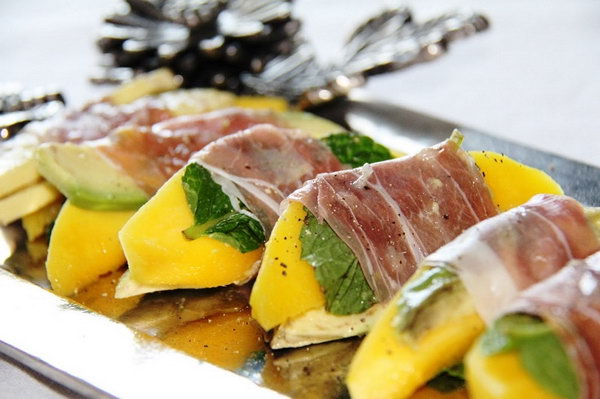 Prosciutto-Wrapped Mango Bites. Serve your guests with this quickly served appetizer. Cut mango into slices, lay each slice on srugula and basil. Wrap mango slices in a strip of prosciutto. Add some pepper for ingredients.
