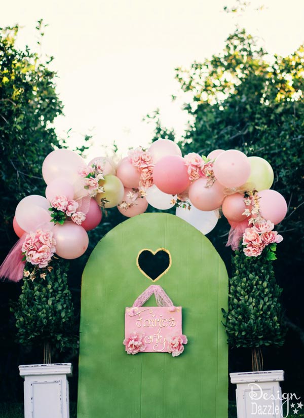 Fairy Gate Party Idea. Decorate your sweet and romantic party with this fairy gate. It has flower bushes in the balloon arch above the topiary. Below the balloon arch is the tall metal garden lantern stakes. I like this fairy style.
