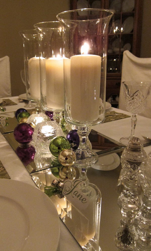 Mirror as a table runner. Look at this amazing table with jingle bells and candles on. It also features the mirror as the runner of the table. It looks super pretty with the candle light reflected by the mirror. 