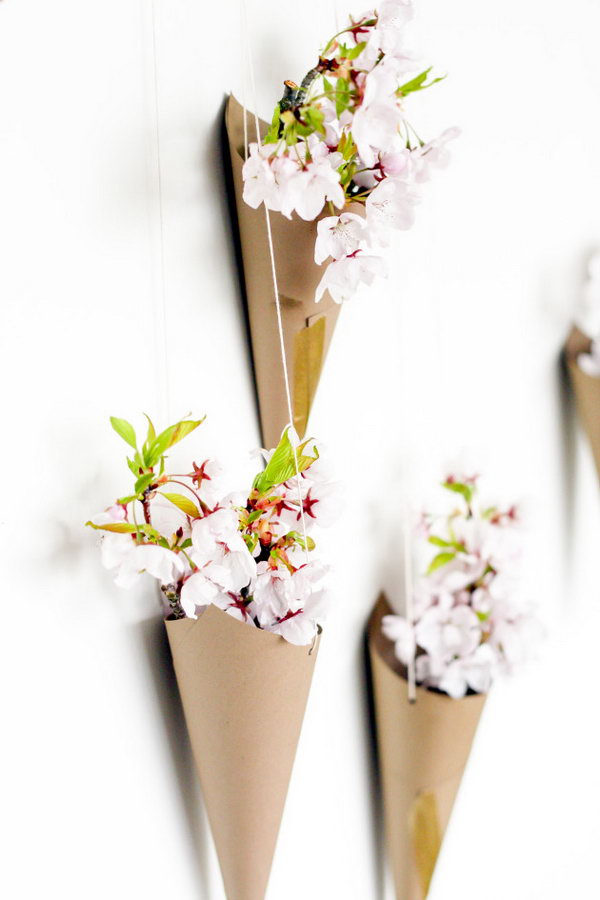 Blossoming Flower Cone Wall Display. Create cones from cardstock, punch 2 holes at both sides, take the string to hang the cone pointed-side down. Arrange the cones on the wall and place some flowers in them to create the beautiful wall art for your dorm room.