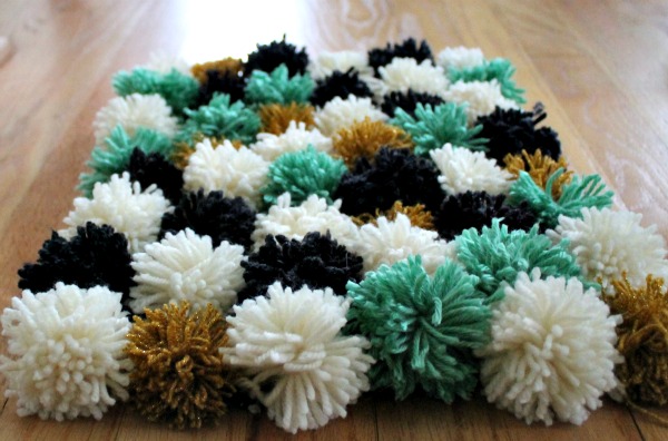 DIY Pom Pom Rug. Choose a color of yarn and wrap it around, tie a strand around the middle and cut the ends to make the pom pom. Create the rug using pom poms as you like. Arrange pieces of yarn in a grid, tie each pom pom to turn out your design to add color, texture and comfort to your dorm room.