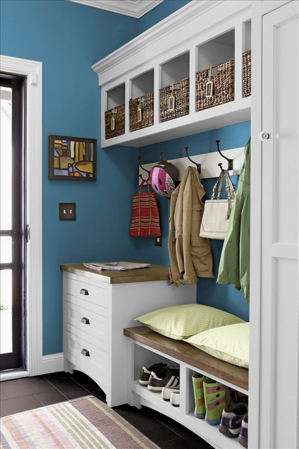  White and blue mud room.  This little mudroom is beutifully made with white and blue color palette, basket storage, big hooks to hang up coats, easy to clean black flooring, bench. 