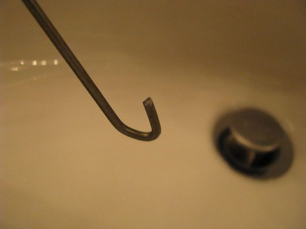 Use a wire coat hanger to form a cook and unclog the drain easily withou calling for drain cleaning service. 