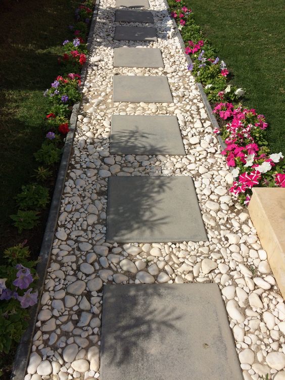 A Simple Pathway with Cement Block Tiles Bordered by White Pebbles . 