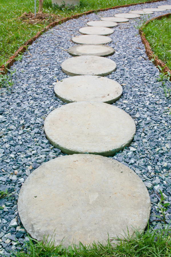  Circular Concrete Stepping Stones Laid On A Darker Gray Set Of Gravel for Pathway. 